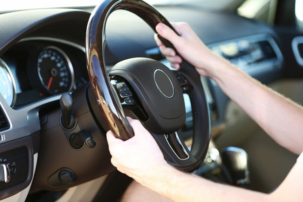 A Person Is Driving A Car With A Wooden Steering Wheel — Goodyear Autocare Bowen in Bowen, QLD