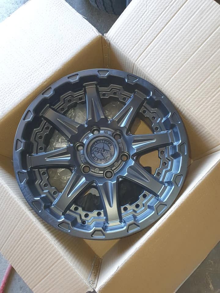 Black Alloy Wheel Rim with Blue Accents Sitting Inside a Cardboard Box — Goodyear Autocare Bowen in Bowen, QLD