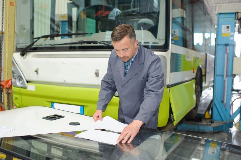 A Man Is Working On The Windshield Of A Bus — Goodyear Autocare Bowen in Bowen, QLD