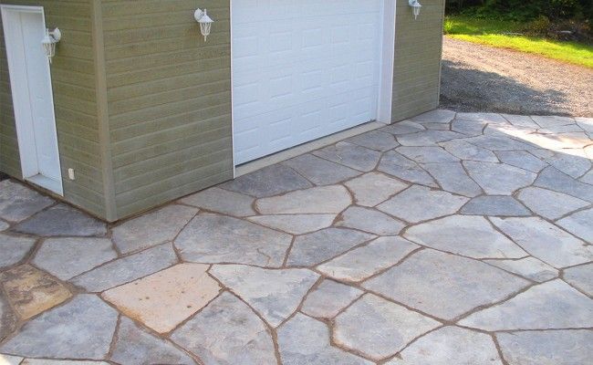 Allée pavée à côté d'un garage avec une porte blanche et un revêtement beige.