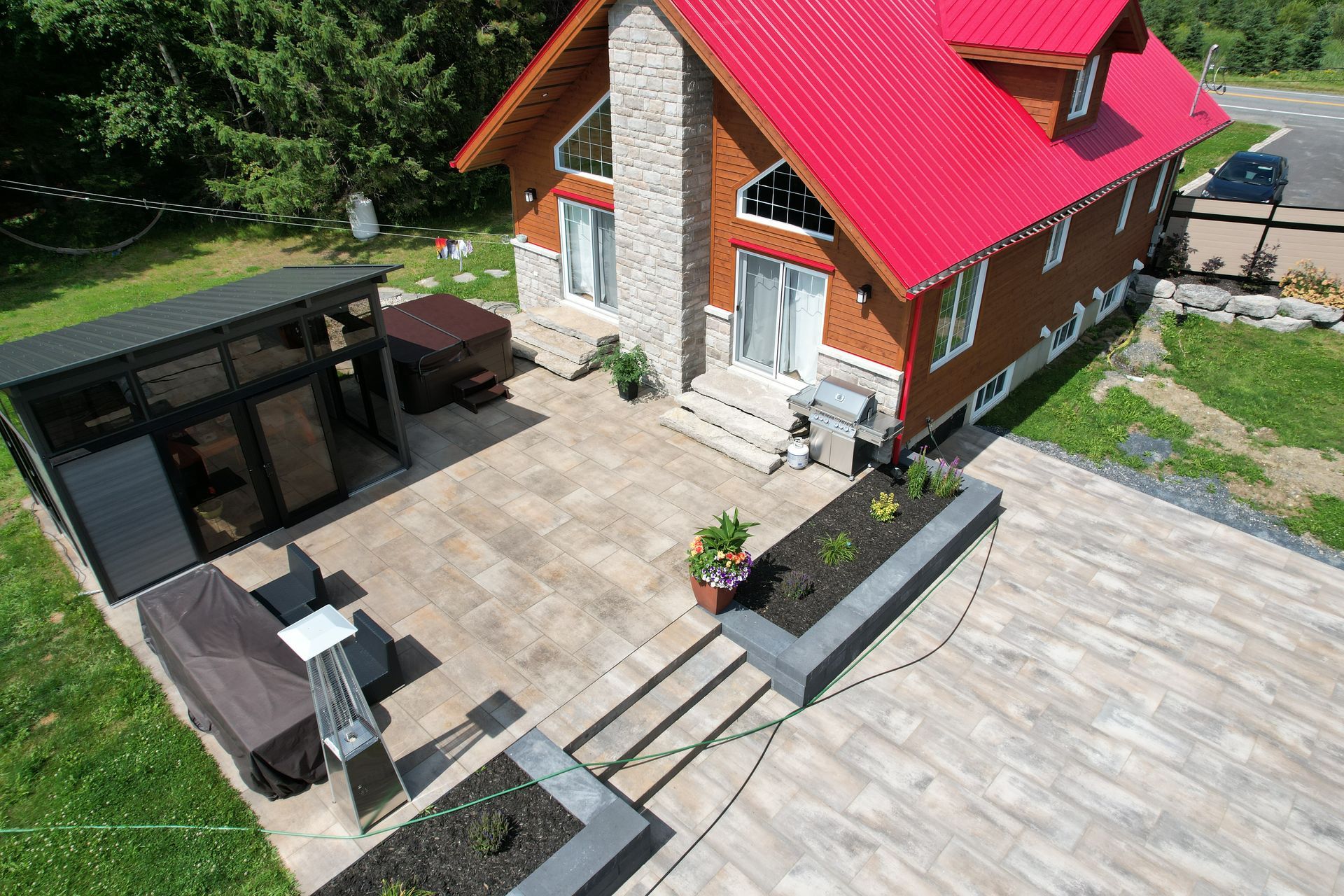 Vue aérienne d'une maison au toit rouge avec un patio, des sièges extérieurs et une grande terrasse en pierre