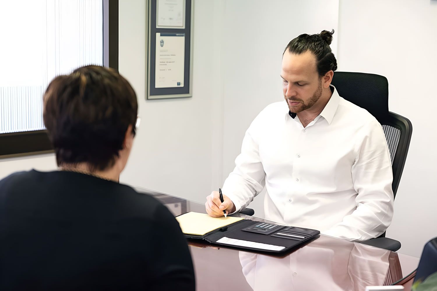 A Man Sits At A Desk, Conversing With Another Man — Whitson Dawson Accountants in Central Queensland