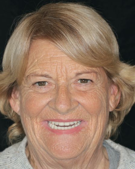 Portrait of a smiling blonde woman against a dark background