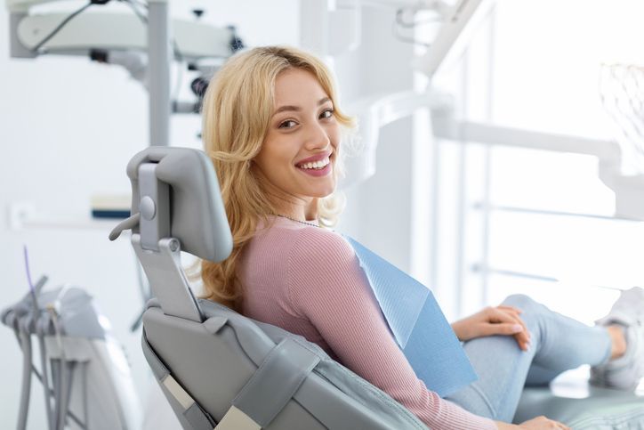 Woman reclining in a dental chair, smiling at the camera in a bright clinic