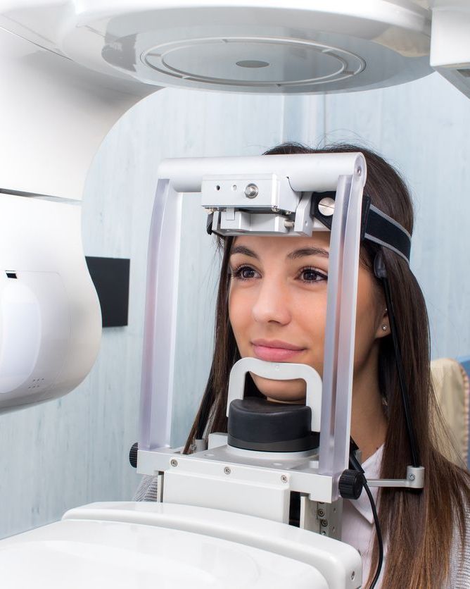 Woman undergoing an eye exam in an optometry machine, with her chin on the rest.