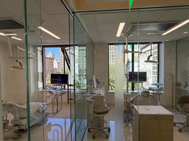 Glass-walled dental clinic with empty treatment chairs and city view through large windows