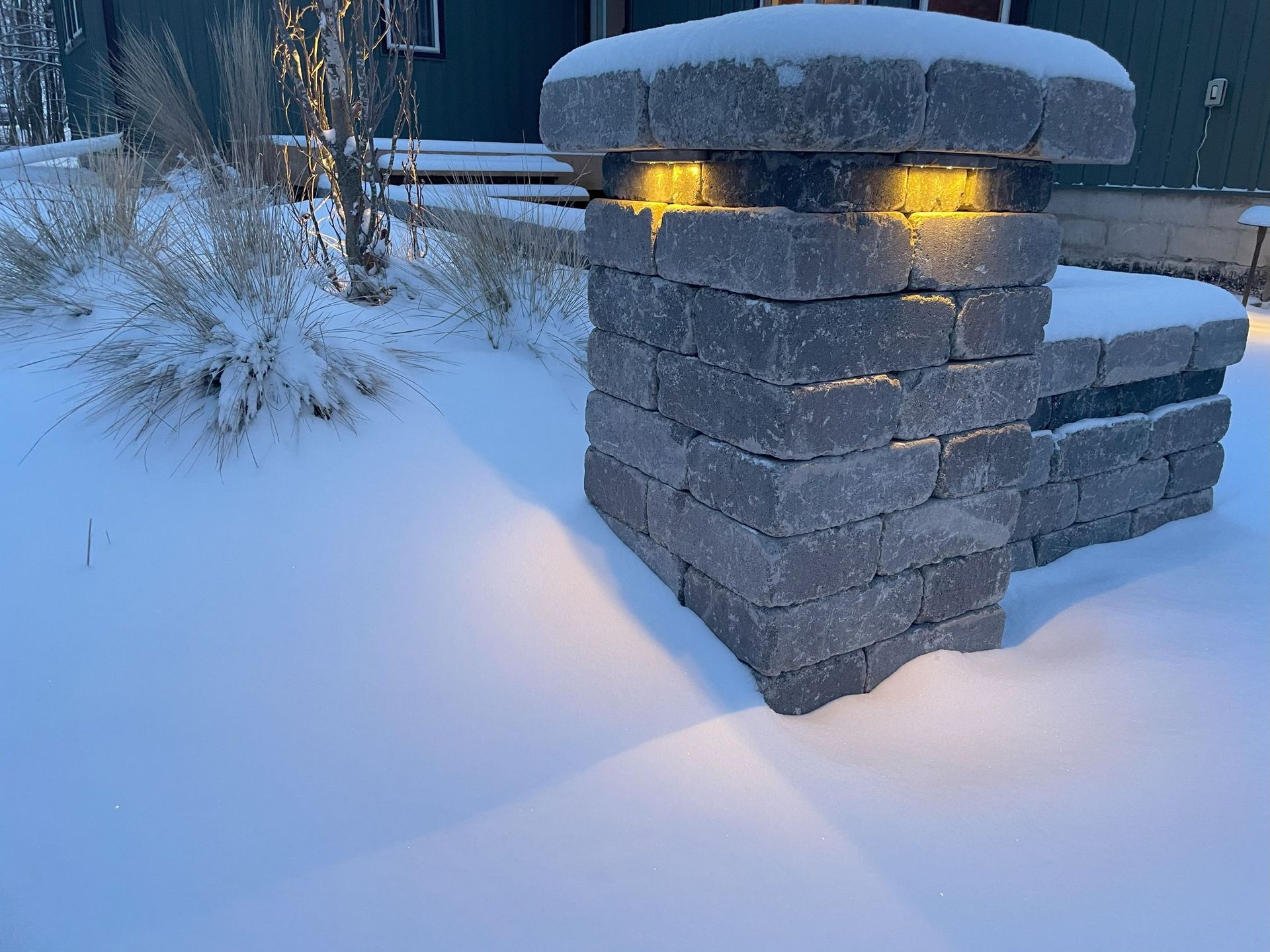 A pergola is lit up at night with a table and chairs underneath it.