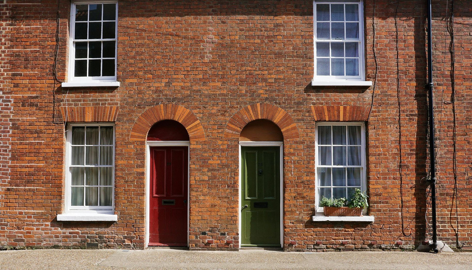 A brick building with two red doors and two green doors