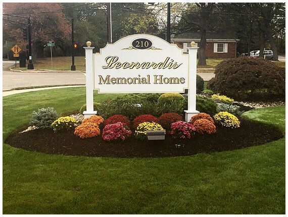Ferrero's Memorial Home sign with flowers in a landscaped lawn at 210
