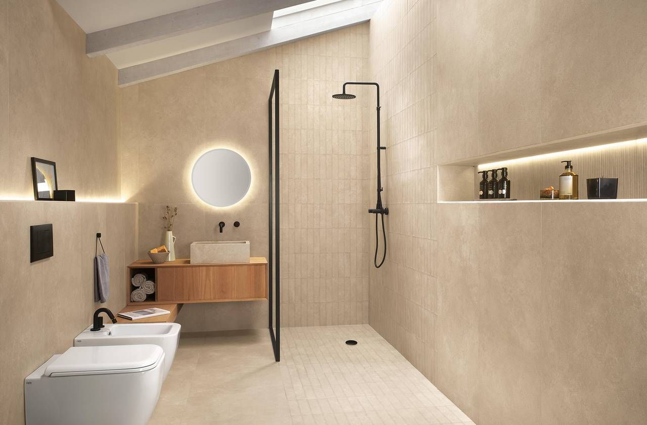 Moderno bagno beige con doccia, lavandino, WC e illuminazione ambientale.