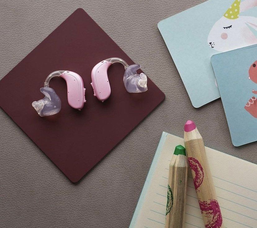 Une paire d'appareils auditifs posés sur un tapis marron