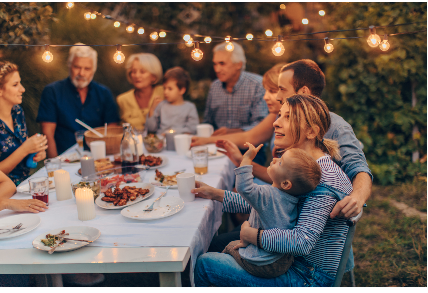 Une grande famille est assise autour d'une table en train de manger de la nourriture.