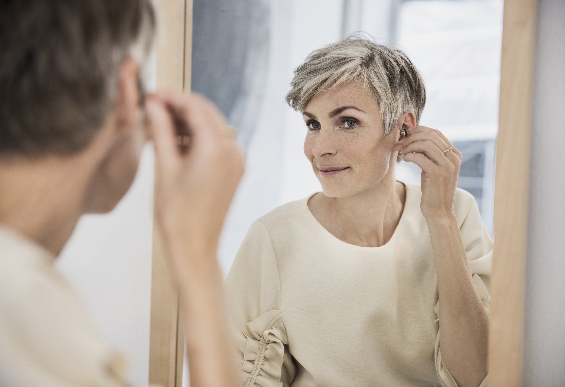 Une femme qui met un appareil auditif adapté à son mode de vie dans son oreille.