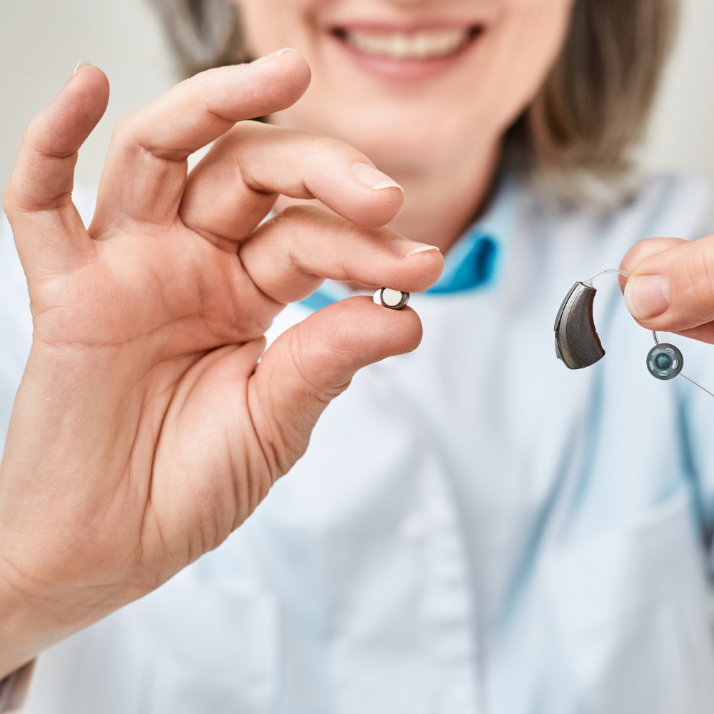 Professionnel de la santé tenant deux types d’appareils auditifs : un modèle intra-auriculaire et un