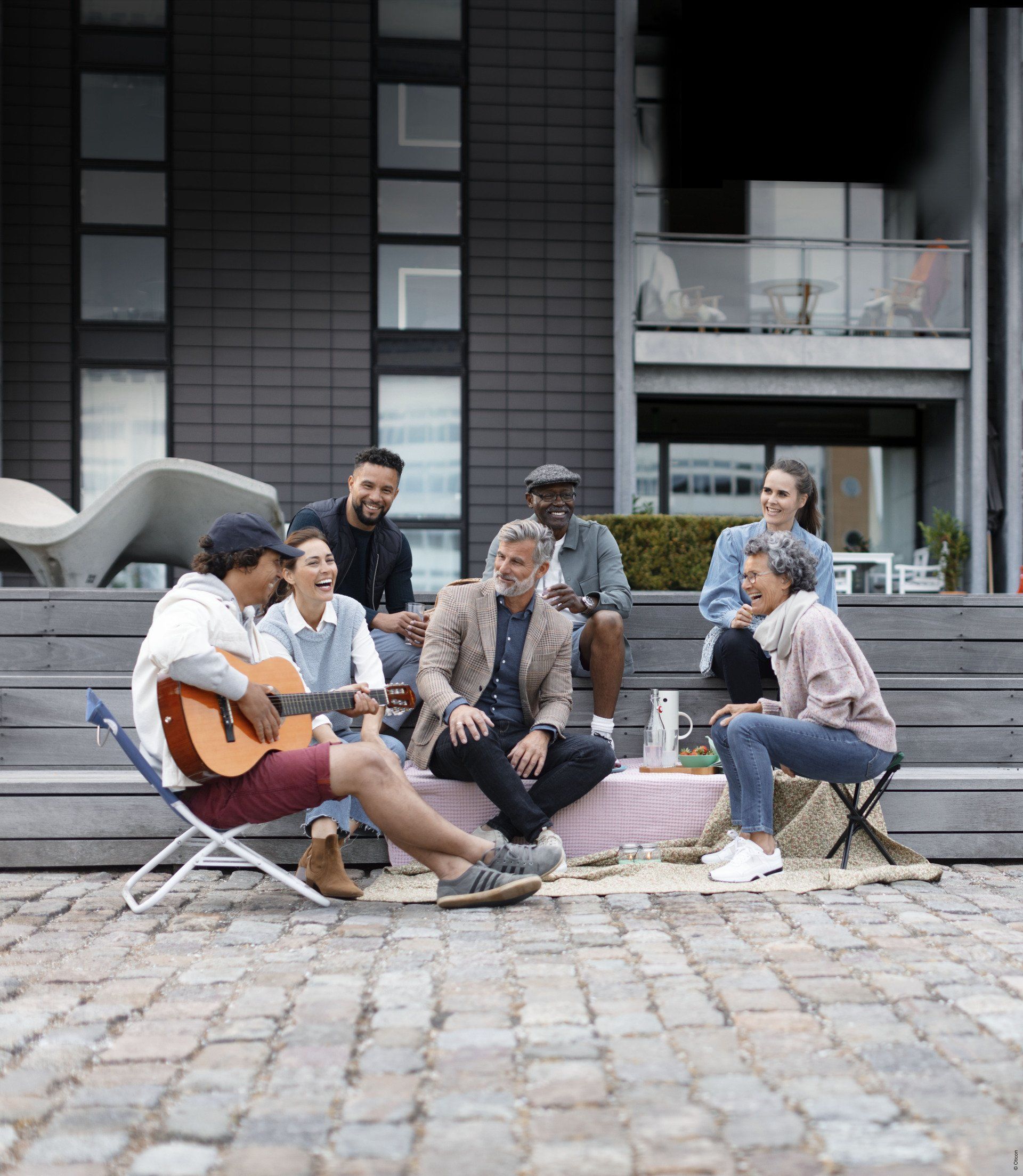 Un groupe de personnes sont assises autour d'un homme jouant de la guitare.