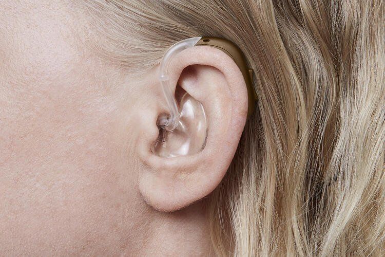 Une femme porte un appareil auditif dans son oreille gauche.