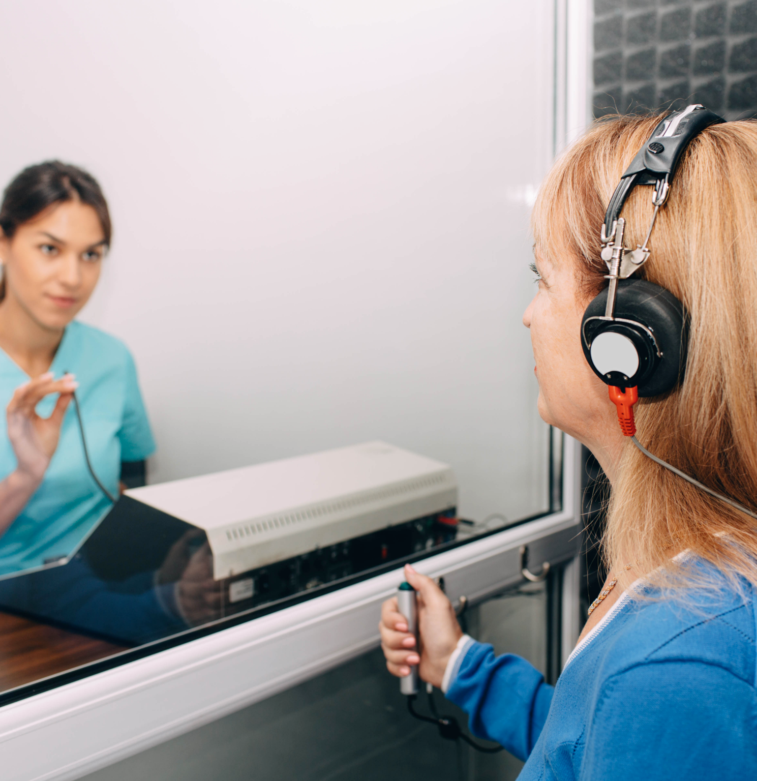 A woman wearing headphones is looking at herself in a mirror