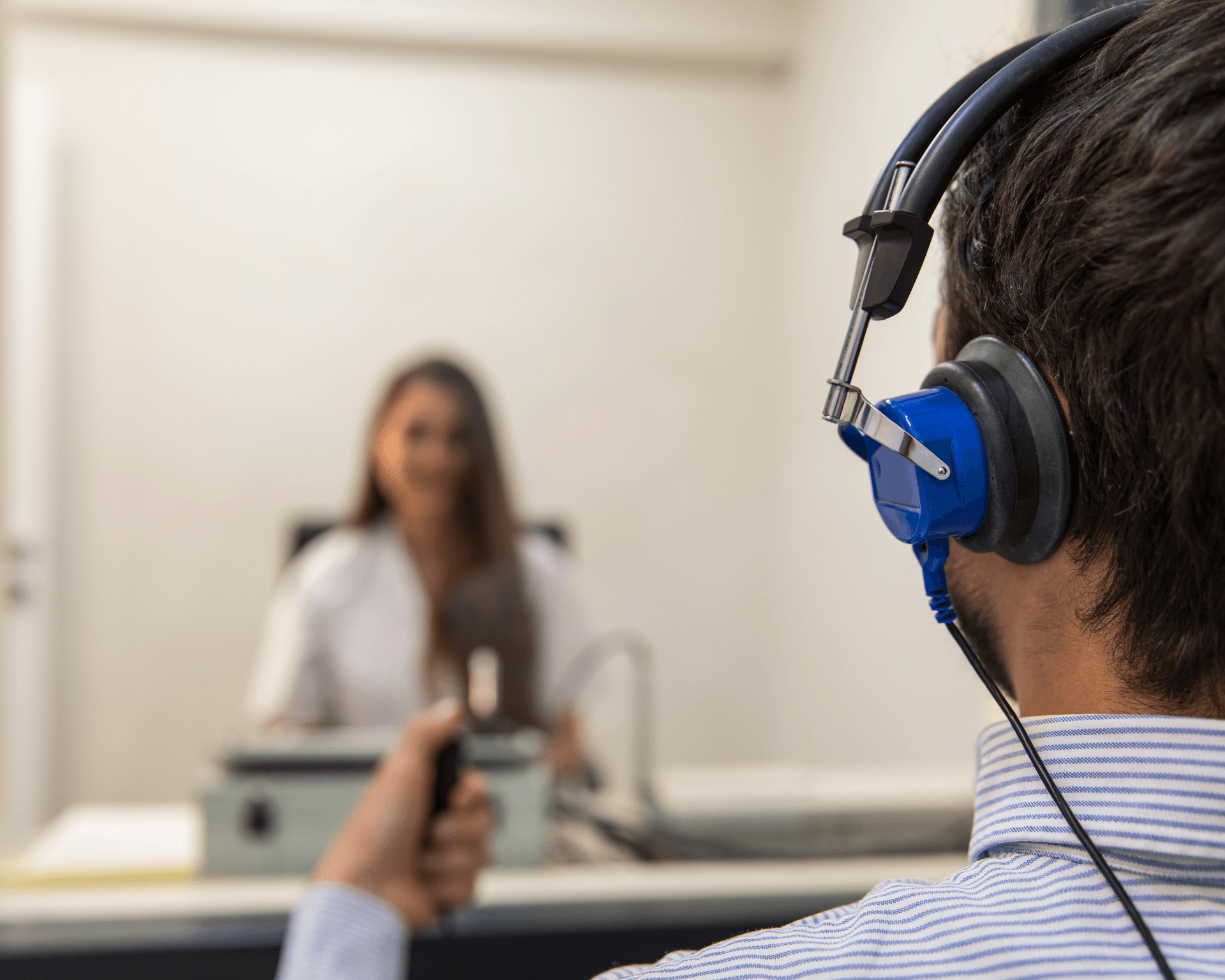 Audiologiste qui effectue un test auditif complet à un patient qui se trouve dans une cabine insonorisée