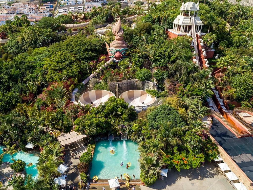 An aerial view of a water park surrounded by trees and a swimming pool.