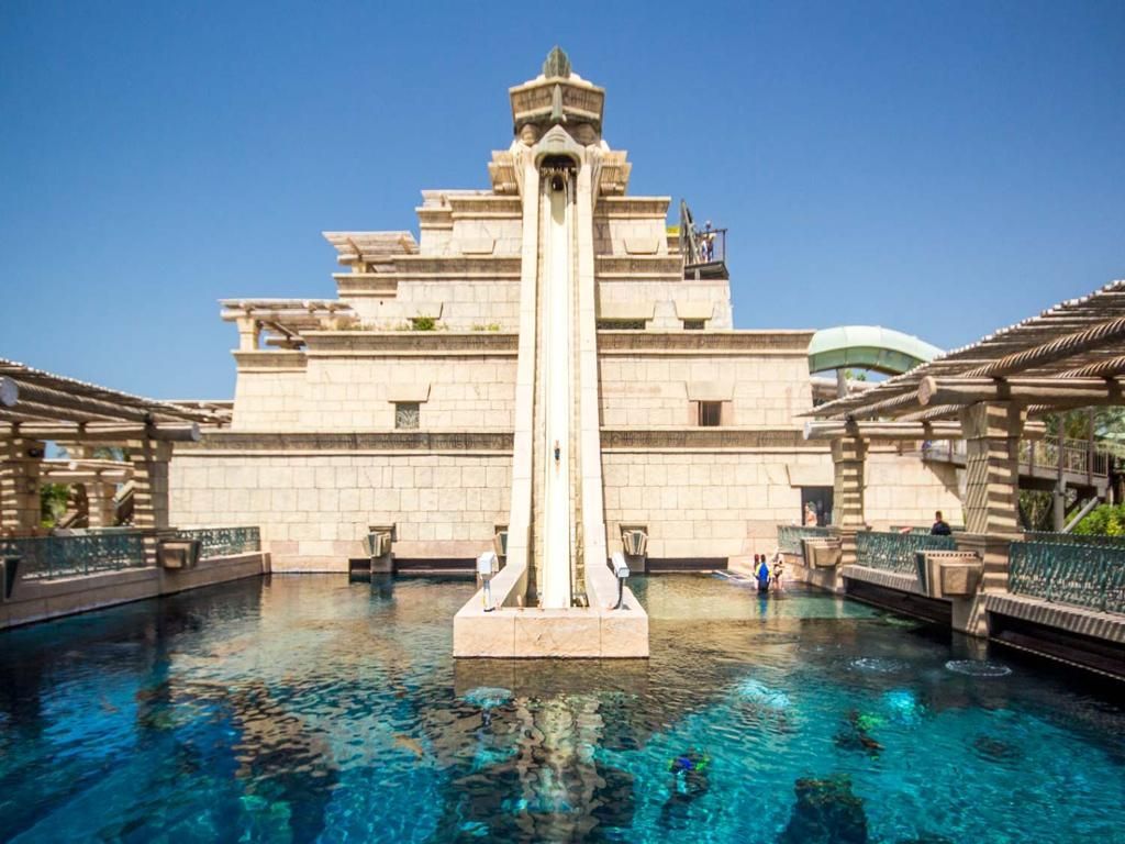 Aquaventure, There is a water slide in the middle of a pool in front of a building.