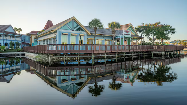 Lakeside resort cottages with a wooden boardwalk reflected in calm water at sunset