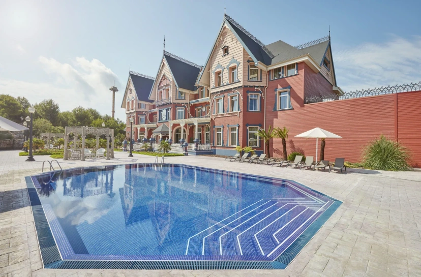 Luxury mansion with a blue outdoor pool and patio under a bright sky