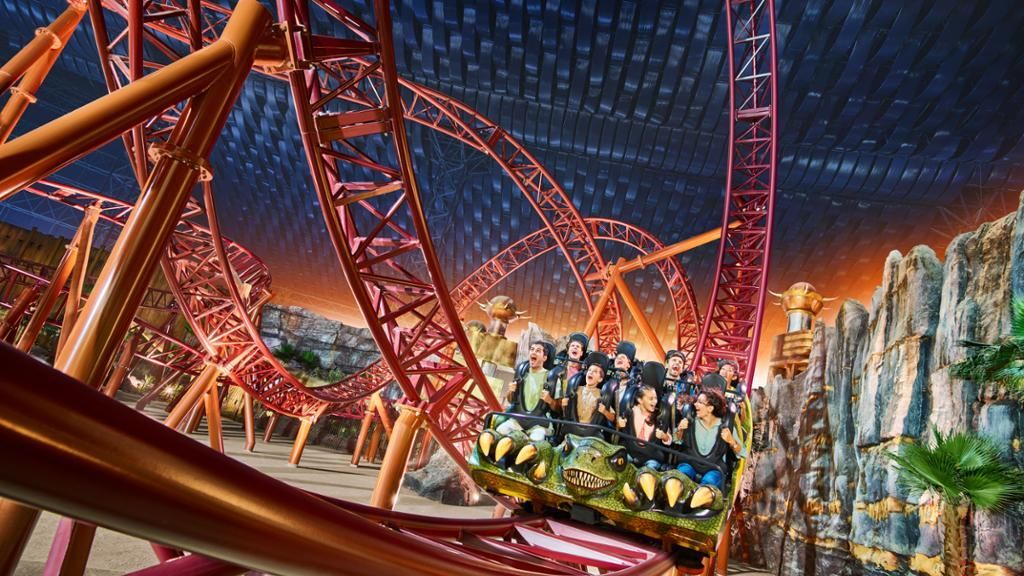 A group of people are riding a roller coaster in an amusement park.