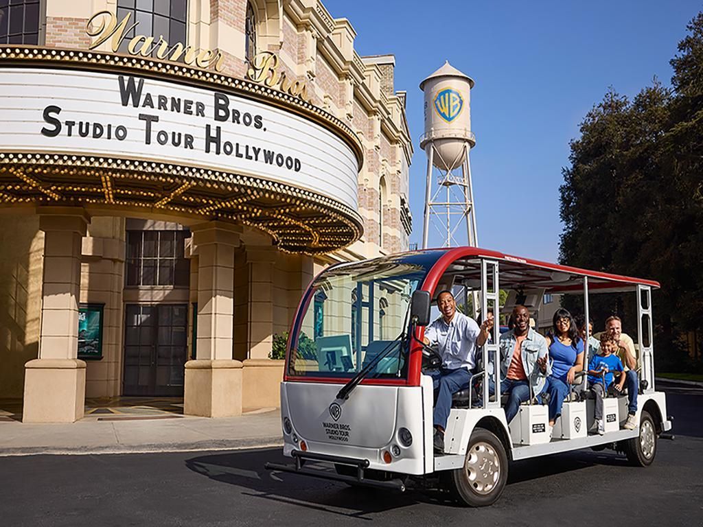 A group of people are riding in a bus in front of a sign that says studio tour hollywood
