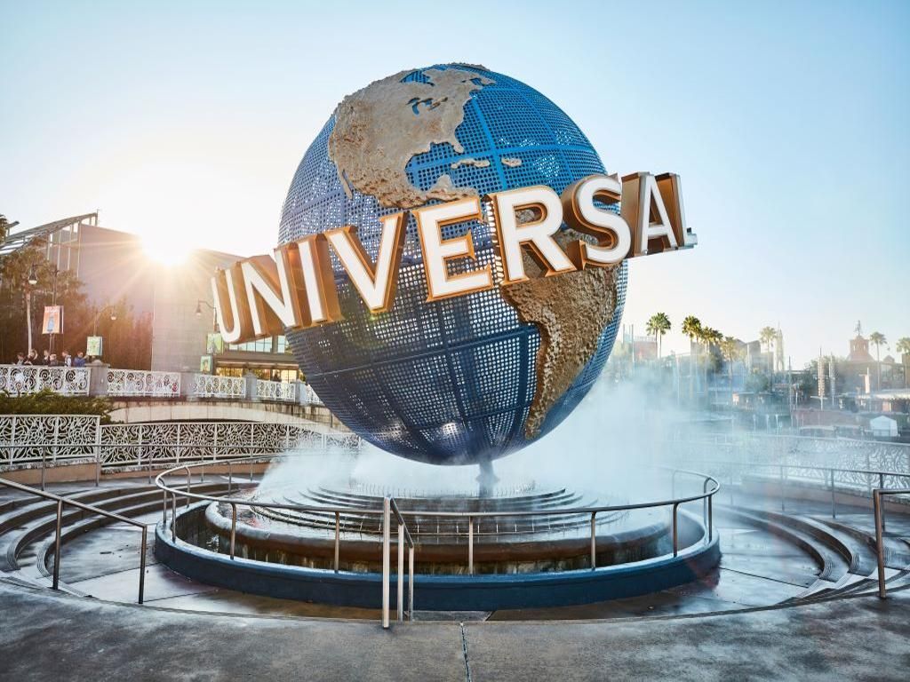 A large globe is sitting in front of a fountain at universal studios.