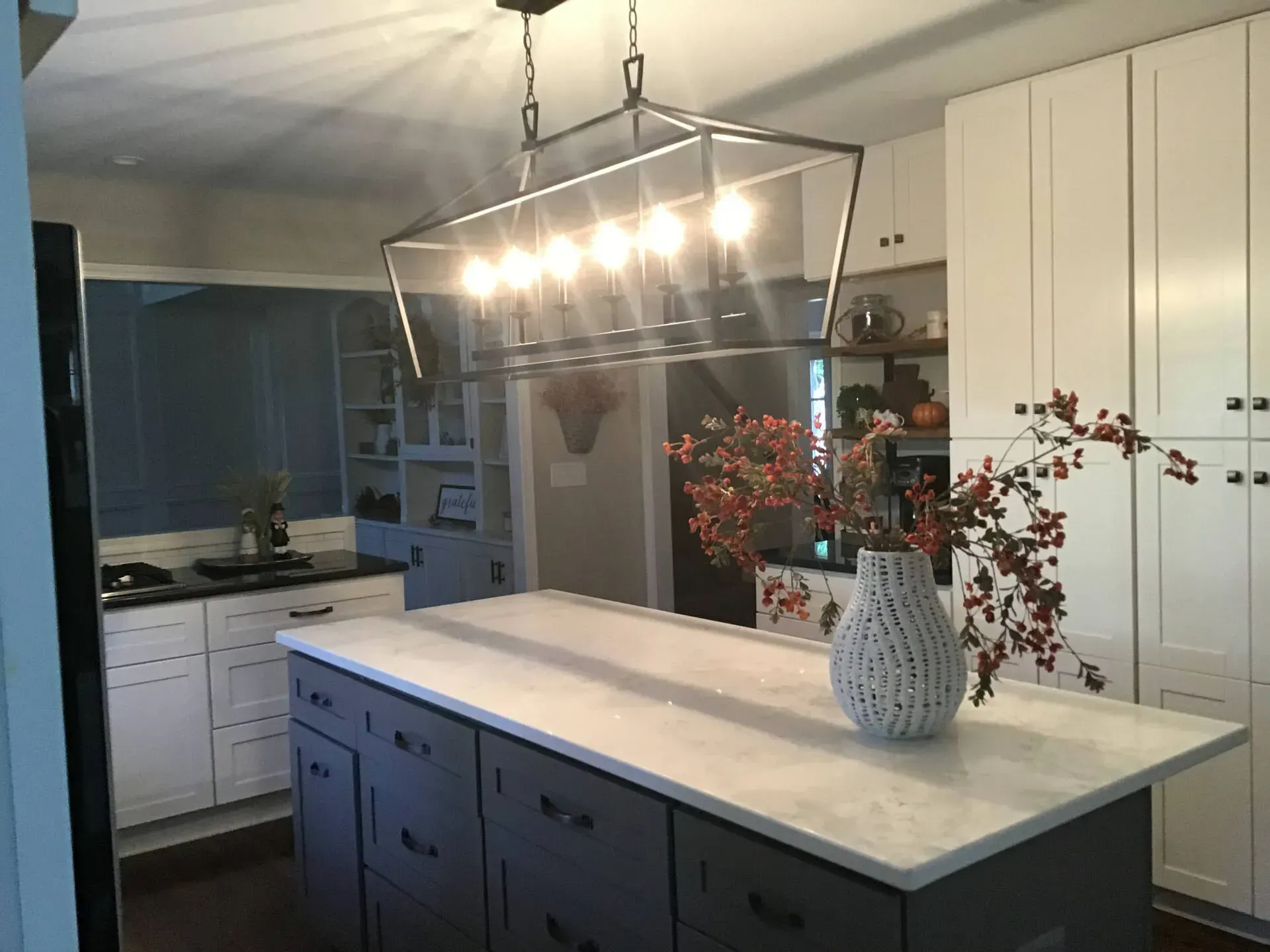 Modern kitchen with island, marble countertop, pendant lights, and vase of flowers