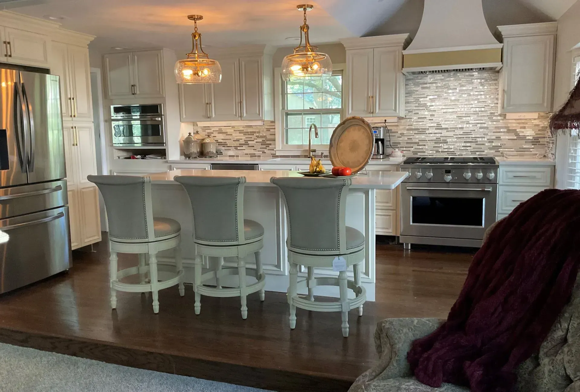 Bright modern kitchen with white cabinets, marble island, pendant lights, and stainless steel appliances