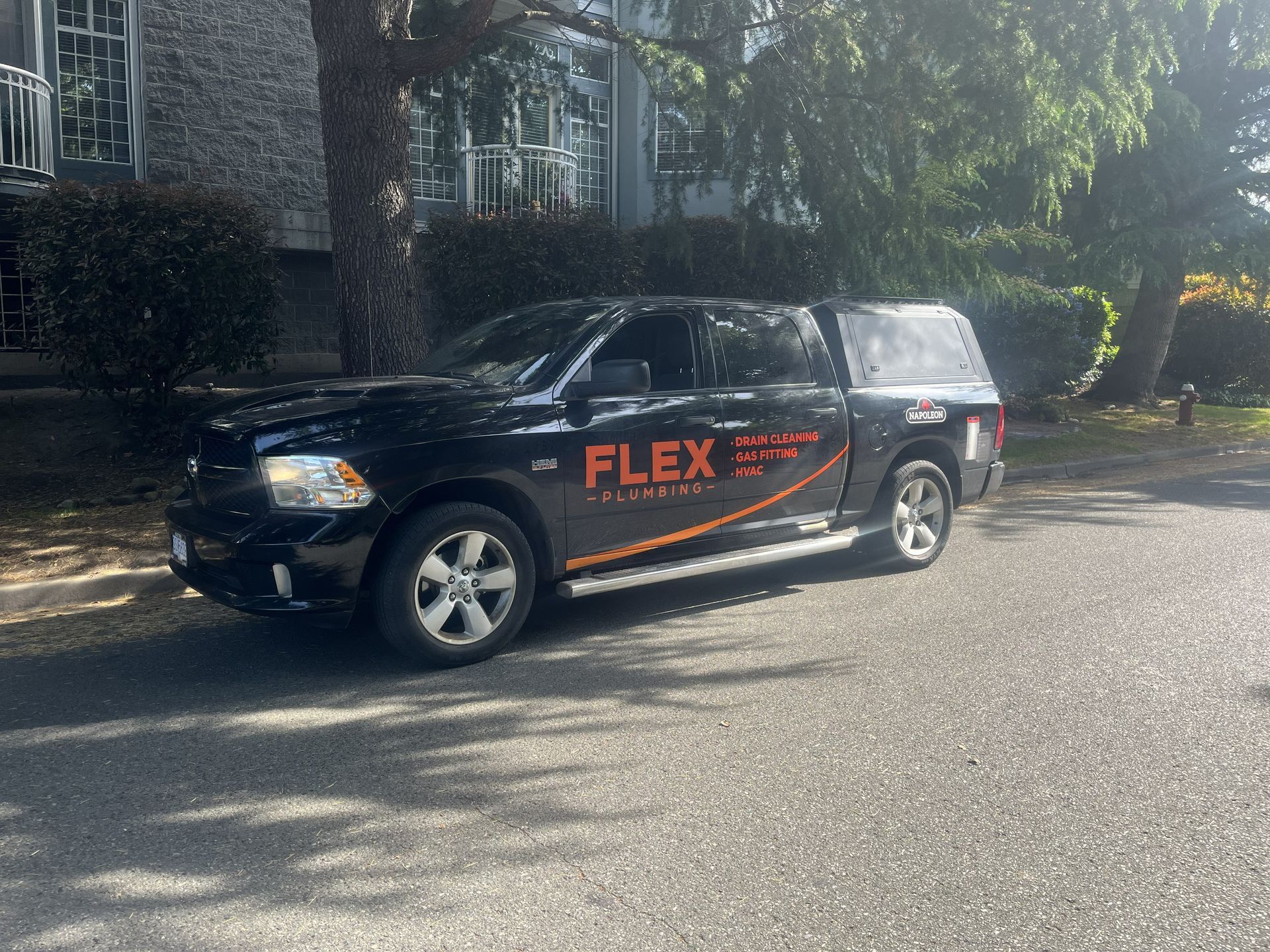 Black Flex service SUV parked on a sunlit street in front of a house