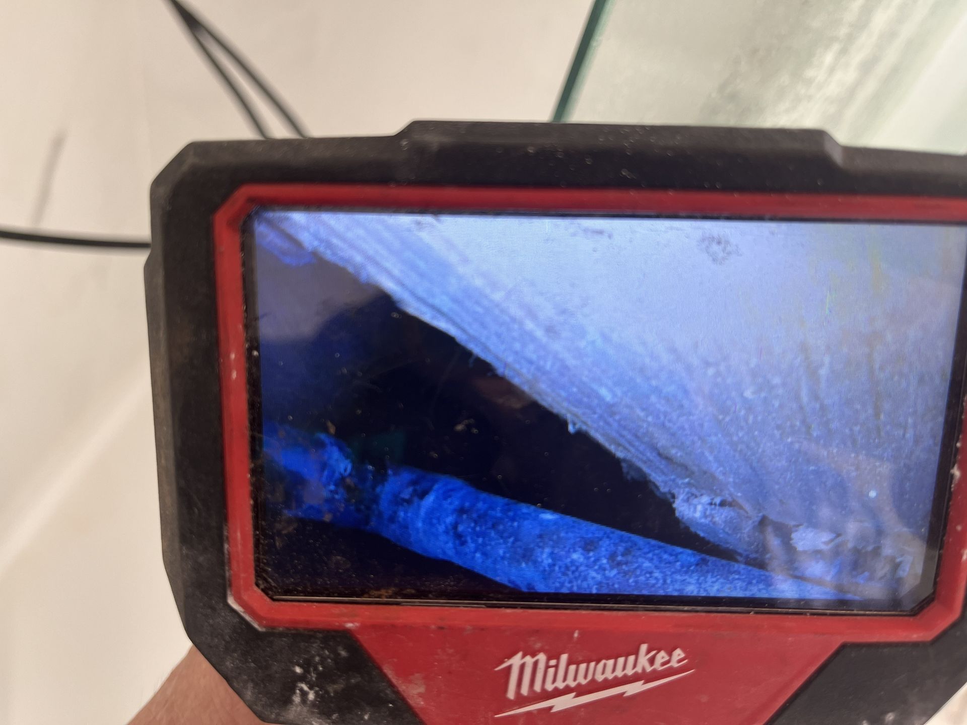 Milwaukee red-framed display showing a blue-tinted close-up of an interior scene