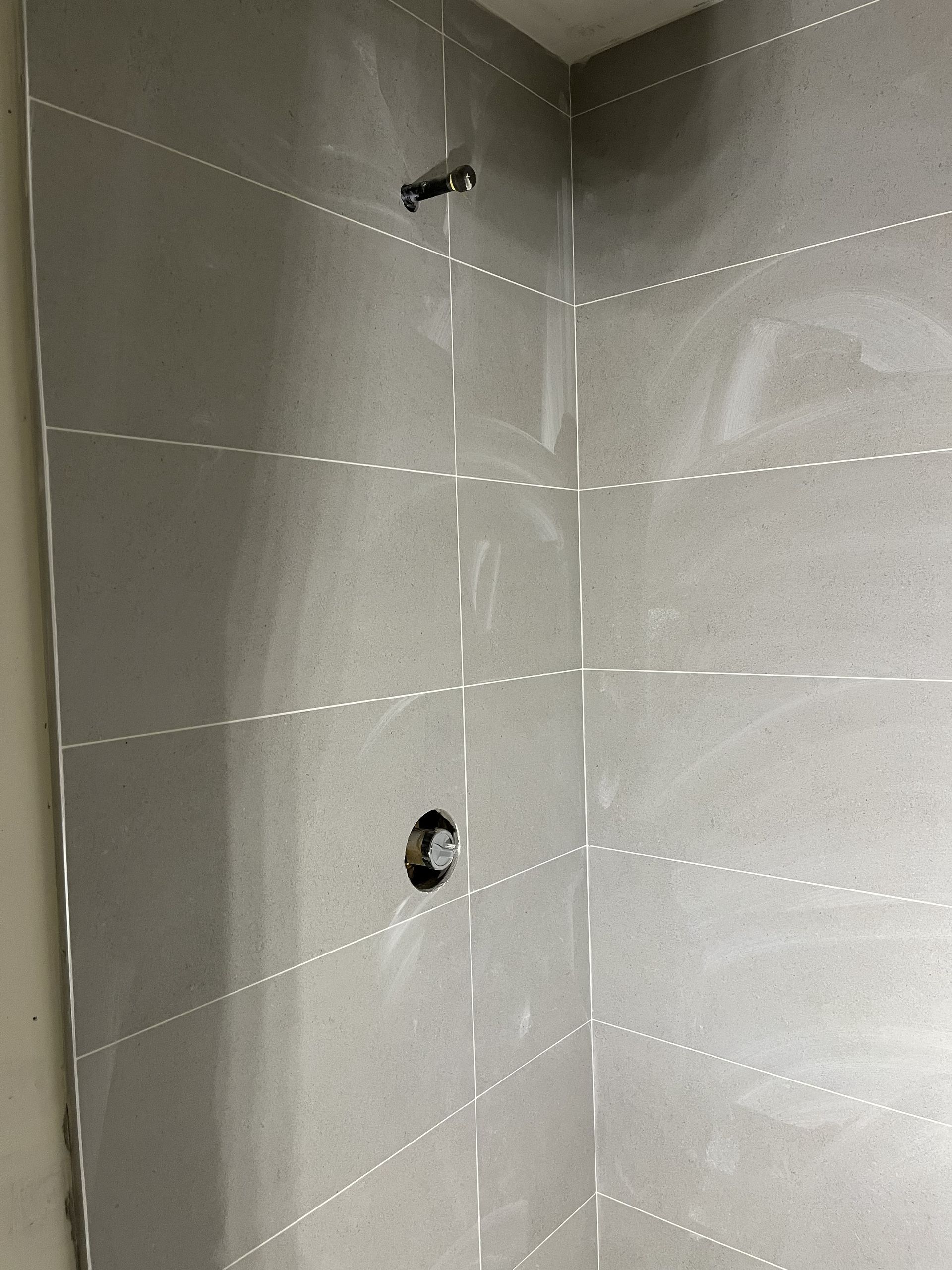Tiled shower wall with two plumbing openings and a showerhead stub-out