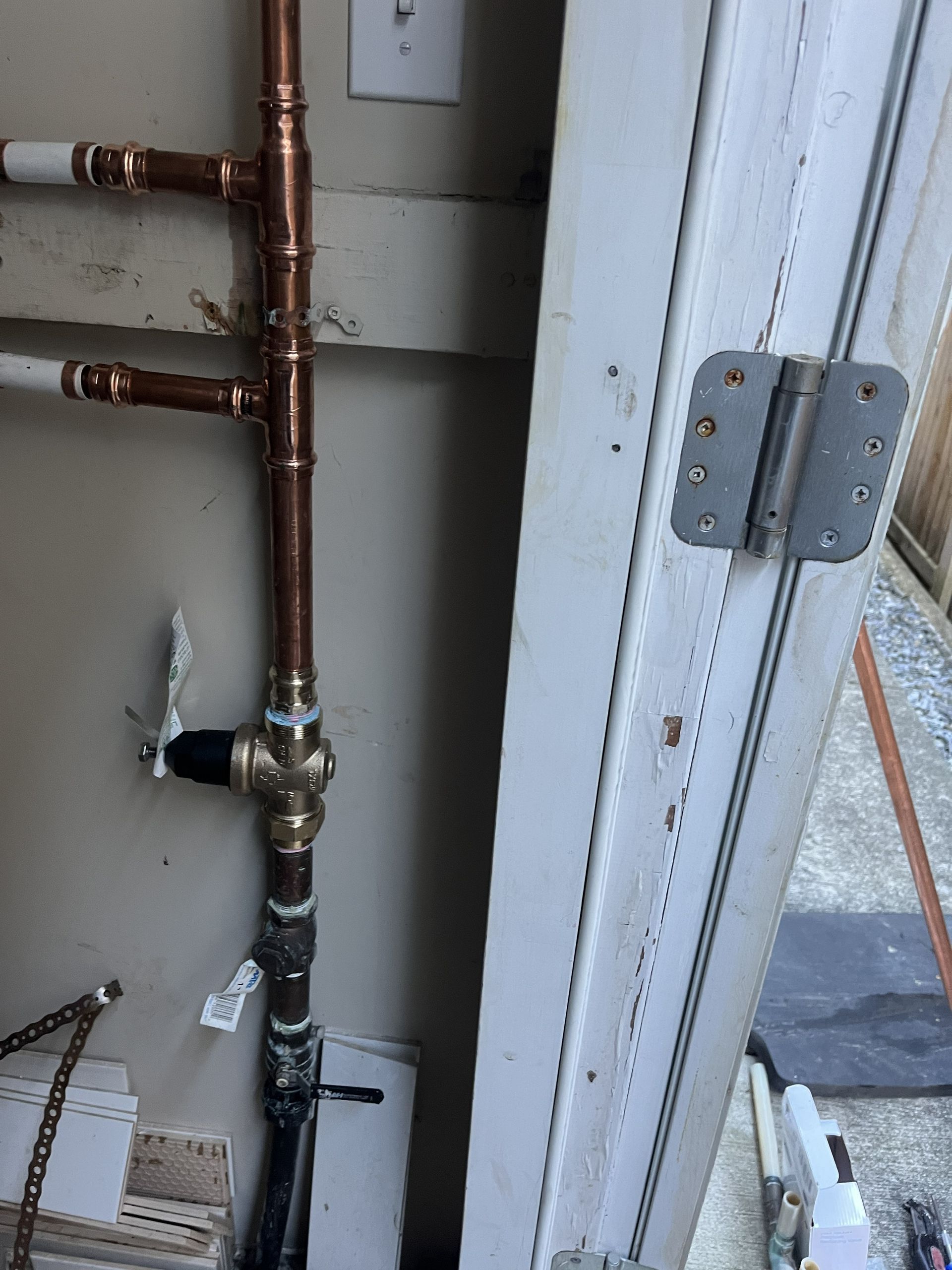 Copper water pipes and valve assembly beside a white door frame indoors