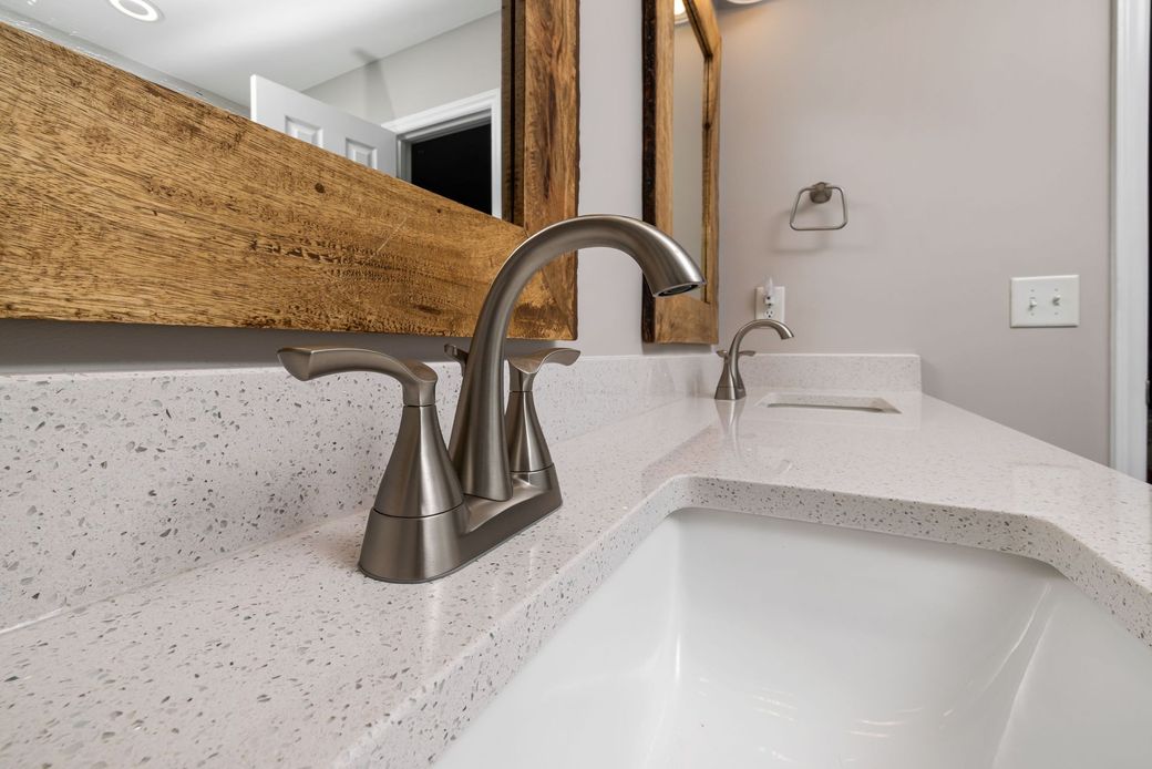 Modern bathroom sink with speckled countertop and brushed nickel faucet near a mirror