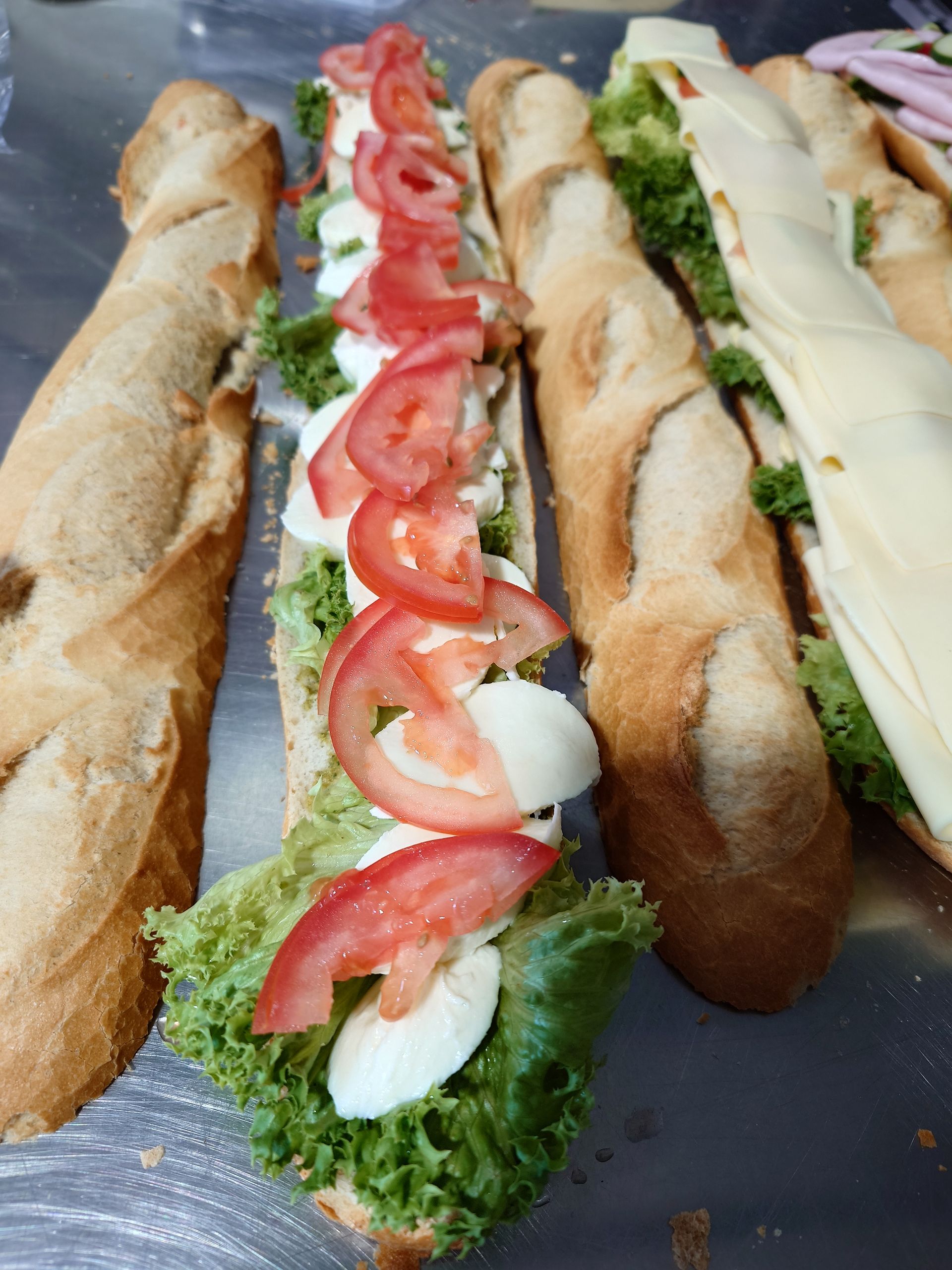 Mit Salat, Tomaten und Mayo belegte Baguettes, auf einem Tablett angerichtet