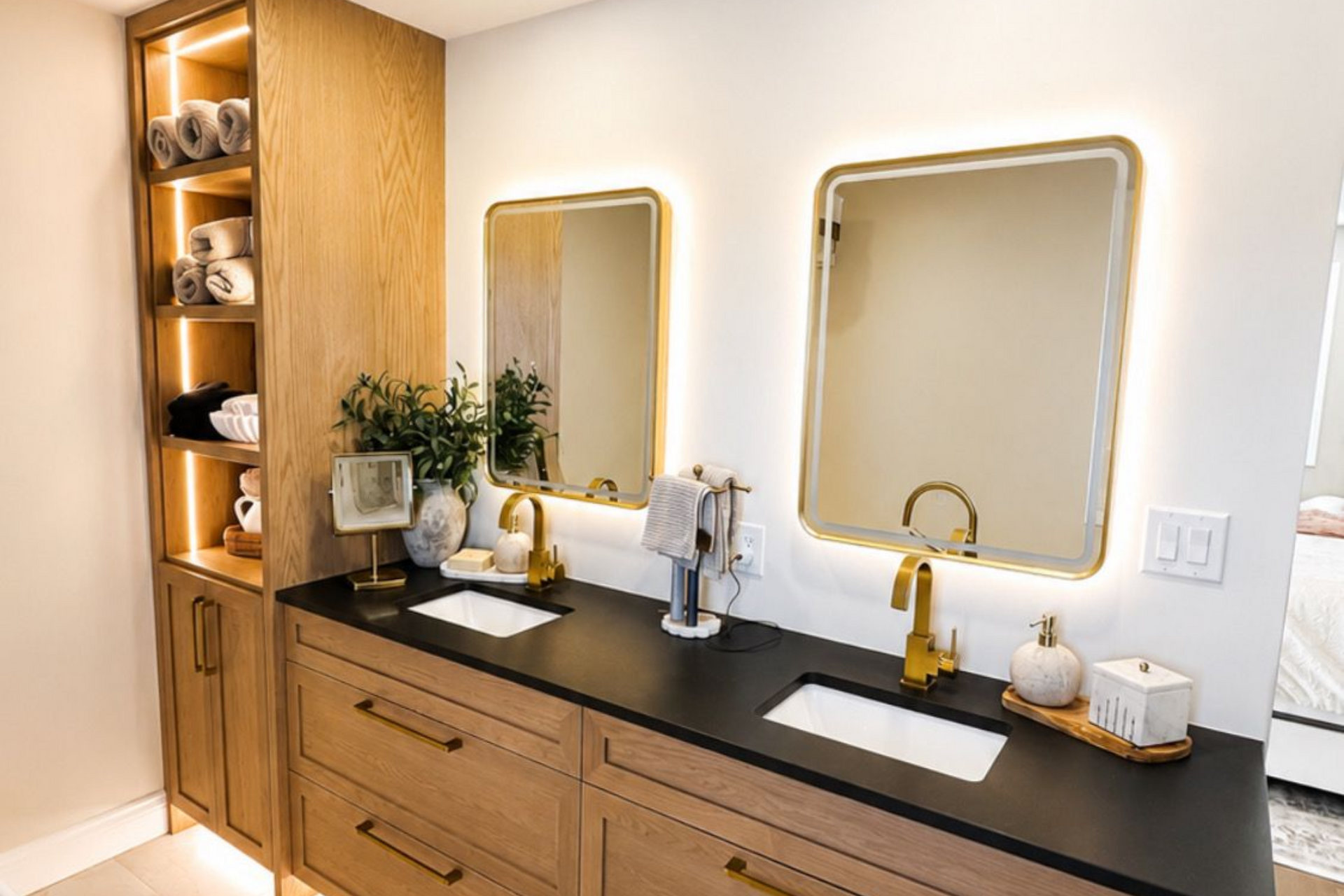 Modern bathroom with double vanity, wood cabinets, black countertop, and two gold-framed mirrors.