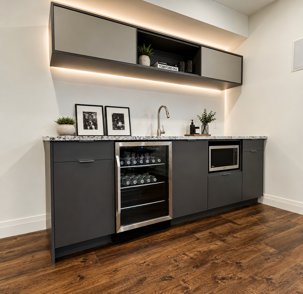 Modern kitchenette with dark cabinets, wine fridge, microwave, open shelves, and wood flooring