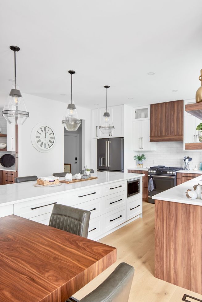 Bright modern kitchen with white island, wood accents, pendant lights, and stainless steel appliances