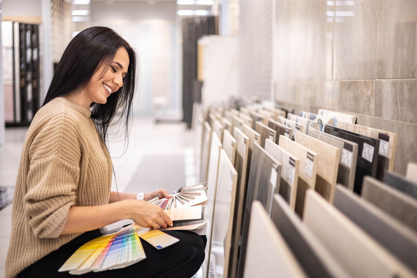 Person browsing paint swatches in a bright store aisle