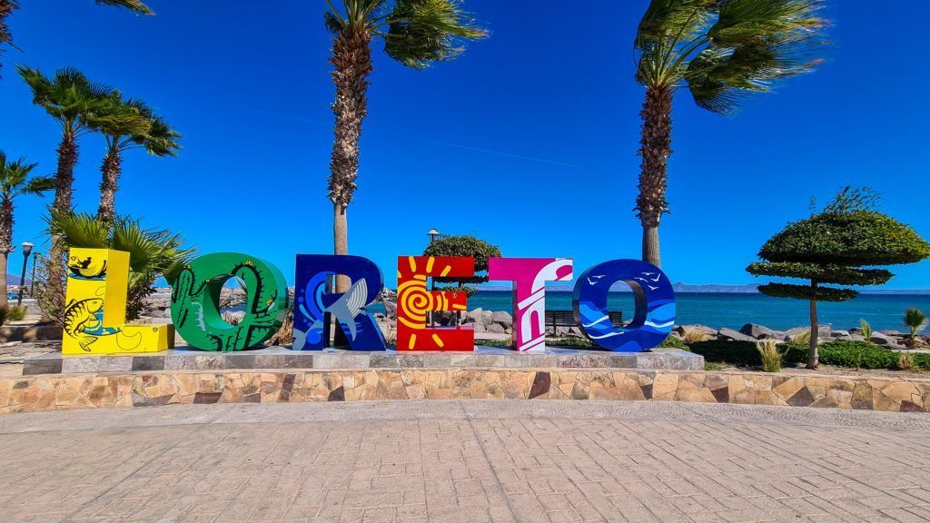 A sign that says loreto in front of palm trees