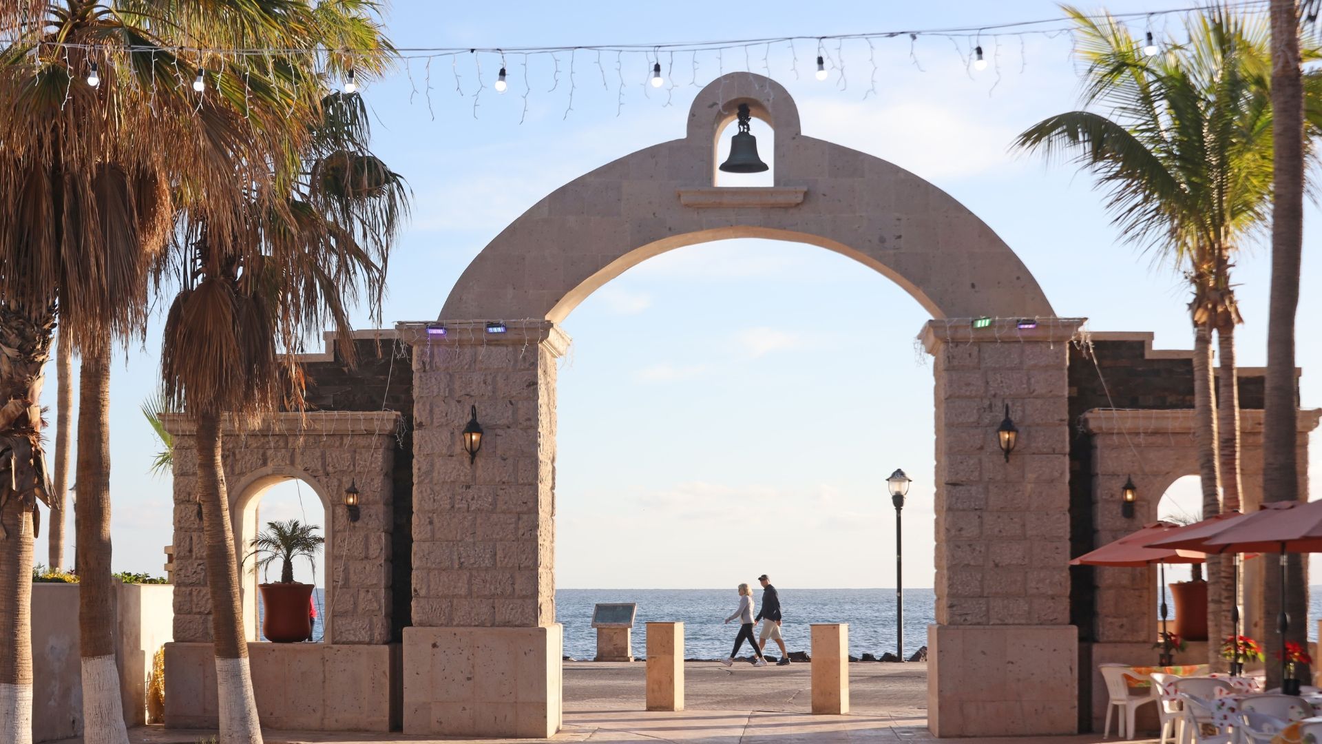 A stone archway with a bell on it leads to the ocean