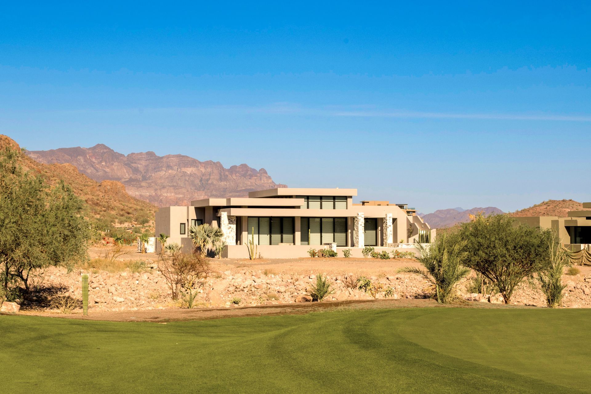 A large house is sitting on top of a hill next to a golf course.