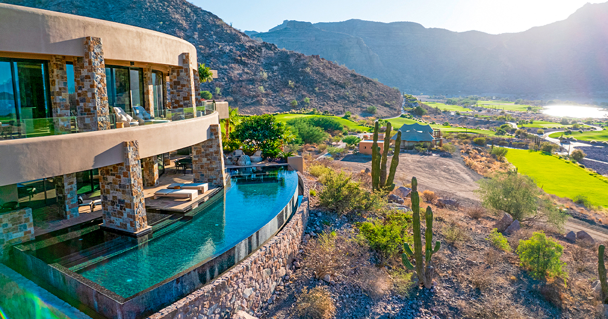 A large house with a swimming pool in the middle of a desert.