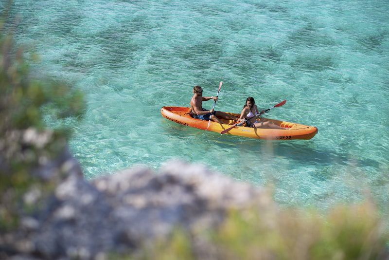 A man and a woman are paddling a kayak in the ocean.