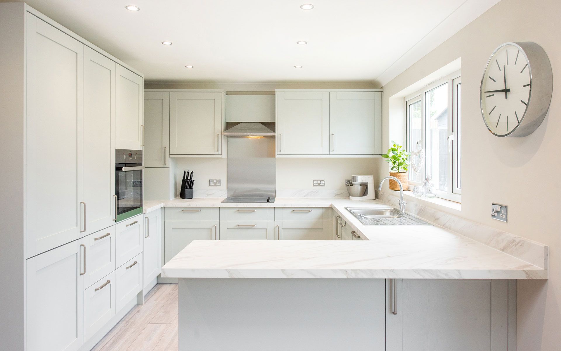 A kitchen with white cabinets and a clock on the wall.