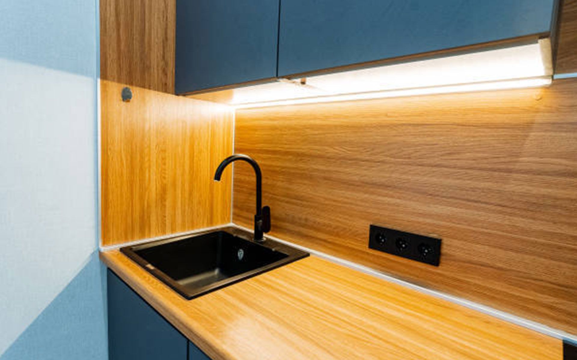 A kitchen with a sink and a wooden counter top.