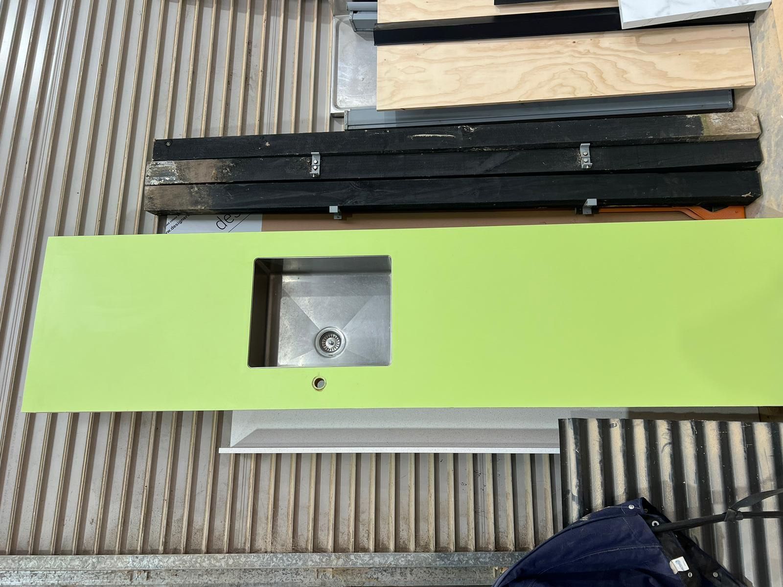 A green counter top with a stainless steel sink