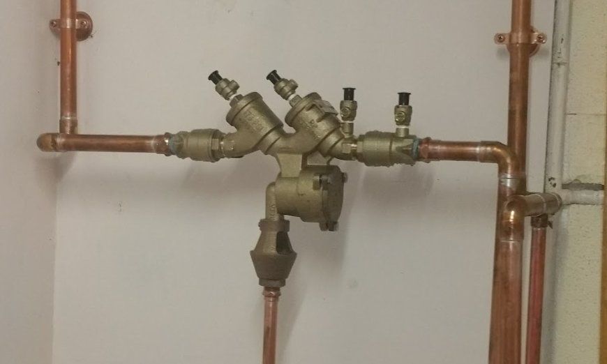 Copper pipes and valves with a pump in a mechanical room.